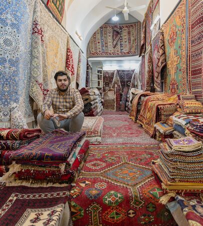Shiraz, Iran - 2019-04-08 - Man sits in his rug carpet store.のeditorial素材