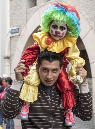 Cuenca, Ecuador - December 24, 2015 - Young father holds his son on his shoulders dressed as a clown to watch a paradeのeditorial素材