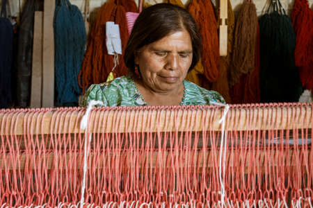 Oaxaca, Mexico - 2019-11-30 - woman works at her loom making a new blanket.のeditorial素材
