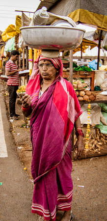 BADAMI, INDIA, MAR 18, 2018: Woman carries her load on her head