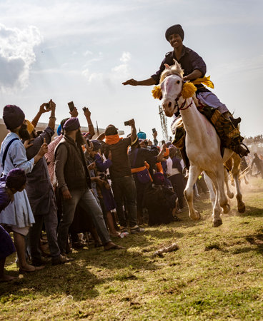 PUNJAB, INDIA, MARCH 2, 2018: Hola Mohalla Festival - Man on horse in full gallop, with all hoofs in the air, races inches past crowdのeditorial素材