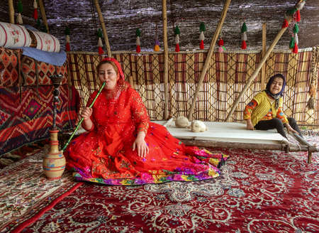 Shiraz, Iran - 2019-04-09 - Qashgal woman smokes water pipe hookah in her tent.のeditorial素材