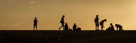 Silhouettes of people watching the sunset on Oahu, Hawaii.