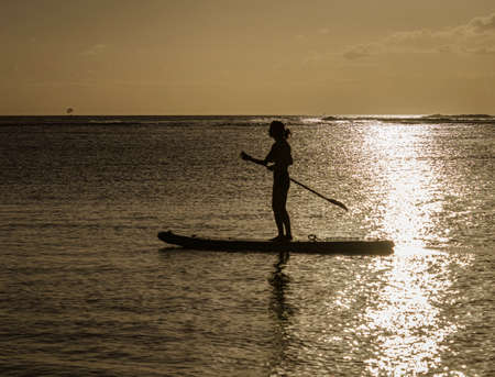 Paddle boarder at sunset on Oahu, Hawaii.