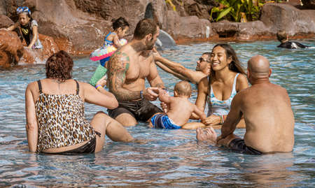 Waikiki, Honolulu, Hawaii - Oct 31, 2021-family playing in a pool surrounded by rocks.