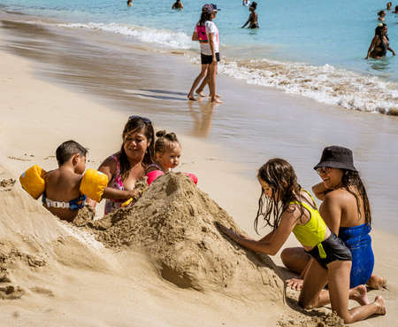 Waikiki, Honolulu, Hawaii - Oct 31, 2021-A family building a sand castle at the beach.のeditorial素材