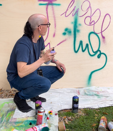 Cuenca, Ecuador, Dec 9, 2021 - Man sprays wall to teach street art (grafitti).のeditorial素材