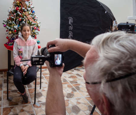cuenca, Ecuador, Dec 11, 2021 - Man with COVID mask photographs youung woman for Christmas card.のeditorial素材