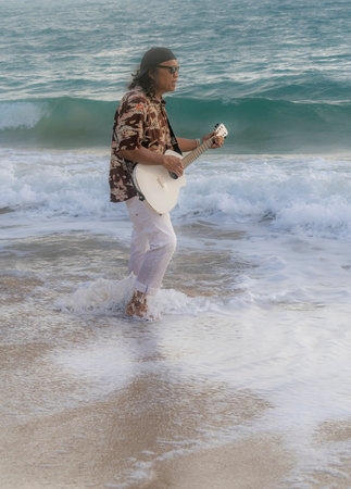 Honolulu, Hawaii/USA - 2022-08-20 - Shaka Filming Hukilau - Musican with guitar walks into the waves near the shore of the ocean.のeditorial素材