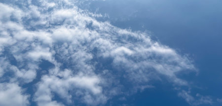 Light cloud patterns dance in the sunny sky. Beautiful and charming blue sky photography, Banner background photos for websites and print.の写真素材