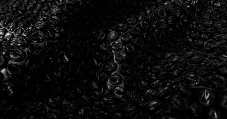 Black bubble wrap with light reflections. Textured background photo. With intricate details for banner, poster and website background.の写真素材