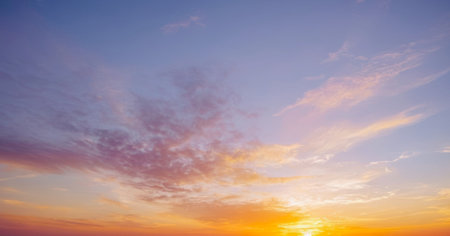 Beautiful sunset sky with pastel pink, purple, orange, and yellow hues, featuring wispy clouds and a warm glow on the horizon.の写真素材