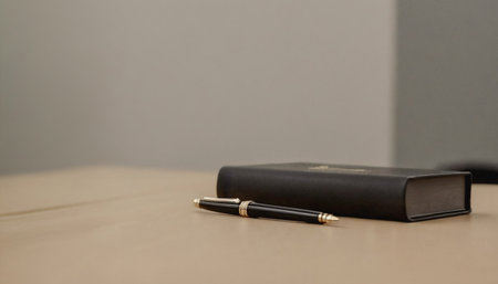 Black pen with gold accents lies next to a closed black leather journal on a light beige surface. Premium photos with modern themes with elegant and luxurious pop colors.の写真素材