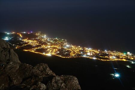 Awesome view from Mount Ai-Petri on the night resort city of Yalta, Crimea, Russia. Cityscape with night city lights on the coast of the Black Sea.の写真素材