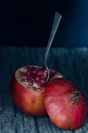 Pomegranate cut with spoon on dark rustic wooden background.の写真素材