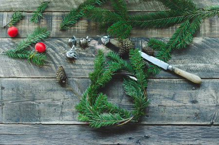 Preparation of pine wreath with christmas decoration on rustic wooden background. Cenital plane.の写真素材