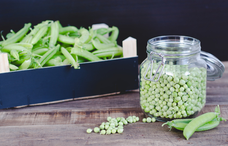 Wooden box and glass jar with peas on wooden bottom.の写真素材