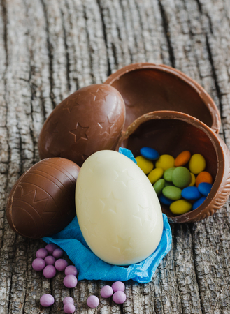Chocolate easter eggs with treats on rustic wooden background. Top view.の写真素材