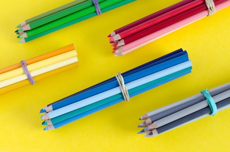 Groups of wooden crayons on yellow background. Top view.