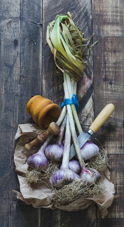 Bunch of garlic with kitchenware on wooden background. Top view.の写真素材
