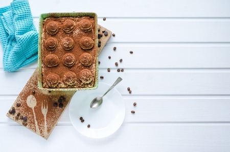 Tray with tiramisu dessert with chocolate on white wooden background. Top view with space to copy.