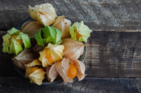 Physalis in bowl on dark wooden background. Uchuva. Space to write.の写真素材