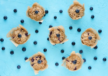 Muffins with blueberries on blue background. Flat lay. Top view.