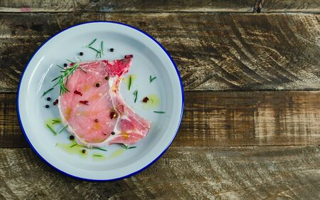 Raw pork chop in white plate on dark background. Copy space Top viewの写真素材
