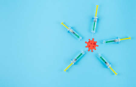 Syringes attacking a red virus cut out of paper. Copy space. Concept Covid-19.の写真素材