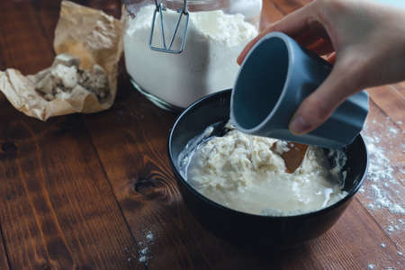 A woman's hand adding water to a bowl of flour to make sourdough. Bakery concept. Copy space.の写真素材