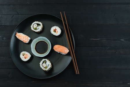 Dish with Sushi and chopsticks on a black wooden background. Copy space. Food concept.の写真素材