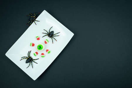 Eye and pieces of candy watermelon with halloween spiders on a black background.の写真素材