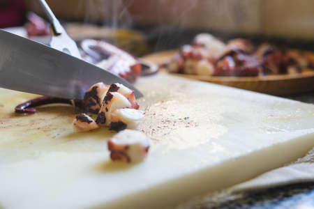 Cutting octopus with knife on kitchen table. Concept of Seafood.
