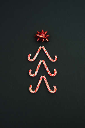Christmas tree with star made with candy canes on a black background. Christmas concept.
