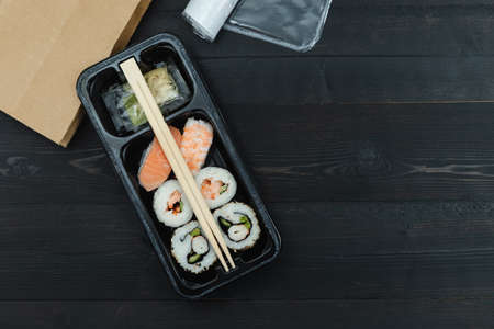 Sushi tray on a black background. Take-away concept. Copy space.