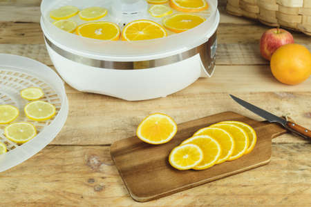 Homemade machine to dehydrate food with orange slices on kitchen table.