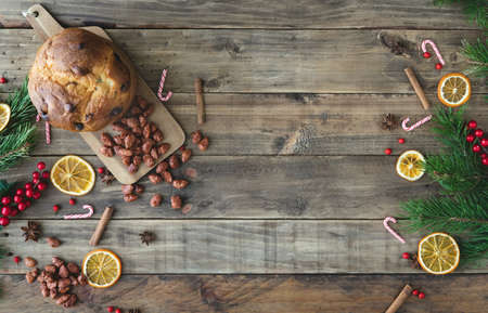 Wooden background with Christmas decorations and dried orange slices and panettone. Copy space. Top...