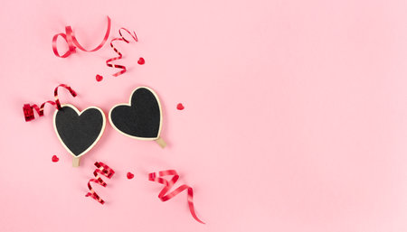 Valentine's Day two black hearts with a light edge with ribbon decoration on a pink background. Copy space.の写真素材