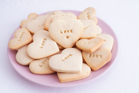 Pink plate with heart shaped cookies and engraved word LOVE. Valentine's Day concept and love.