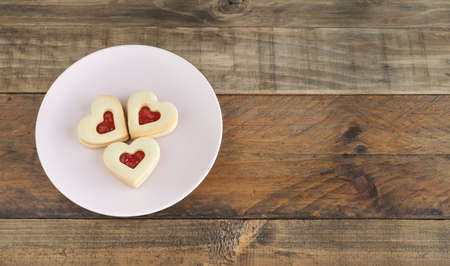 Dish with three heart-shaped cookies on a wooden base. Copy space. Concept Valentine's Day, Mother's Day, anniversary.の写真素材