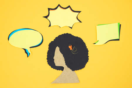 Silhouette of female head with afro hair and several empty comic balloons, cut out on paper on cream background. Copy space.の写真素材