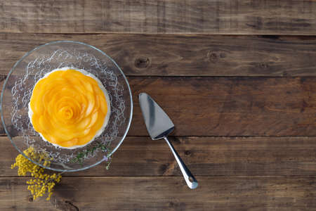 Three milks dessert with jelly decorated with peaches on a wooden base. Copy space. Top view.