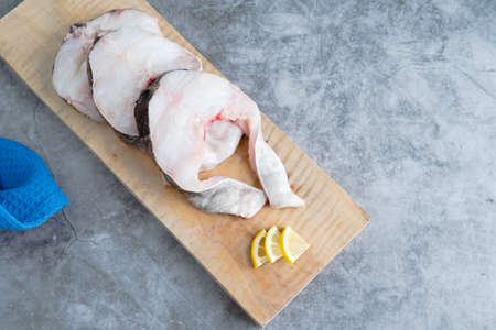 Slices of cod on wooden board on marble background. Copy space. Fresh fish concept.の写真素材