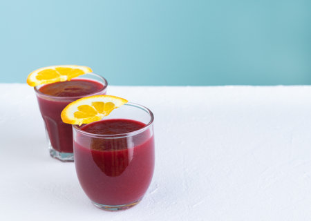 Beet juice on white and blue background with orange slices decoration. Copy space.