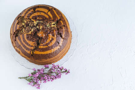Zebra sponge cake on white background with heather flower decoration. Copy space. Top view.の写真素材