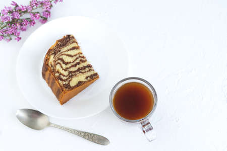 Zebra cake with coffee on white background. Piece of sponge cake on white plate. Copy space. Kitchen...