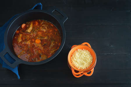 Lamb stew with vegetables and couscous on a black background. Ramadan concept. Copy space.