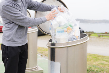 Man throwing plastic containers at plastic recycling point. Social responsibility. Recycling concept. Copy space.の写真素材
