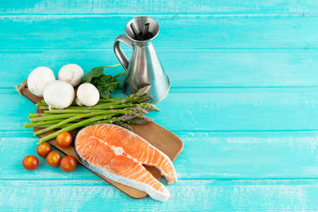 Slice of fresh salmon with vegetables on blue background. Copy space.の写真素材