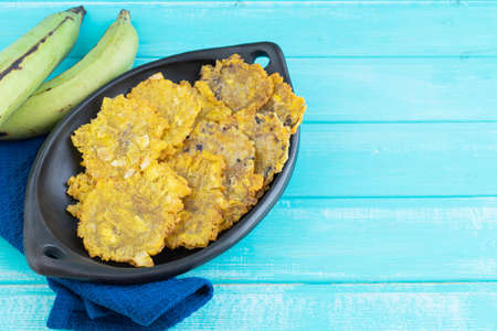 Fried patacones in black dish on blue wooden background. Copy space.の写真素材